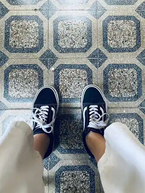 Black and white sneakers viewed from above on a stylish tiled floor.