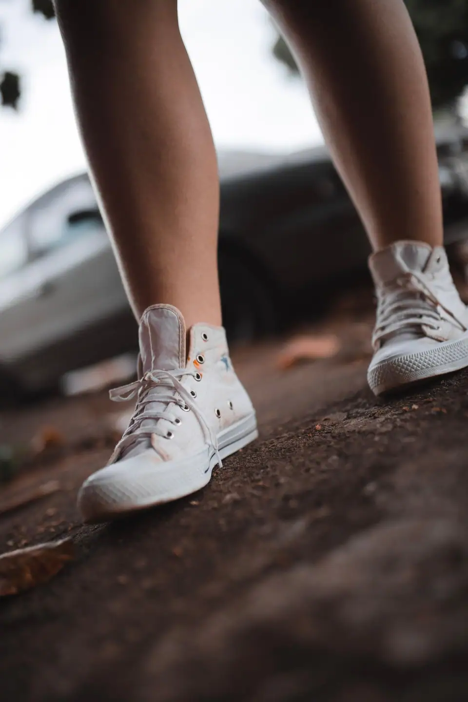 White canvas high-top sneakers worn on a city sidewalk